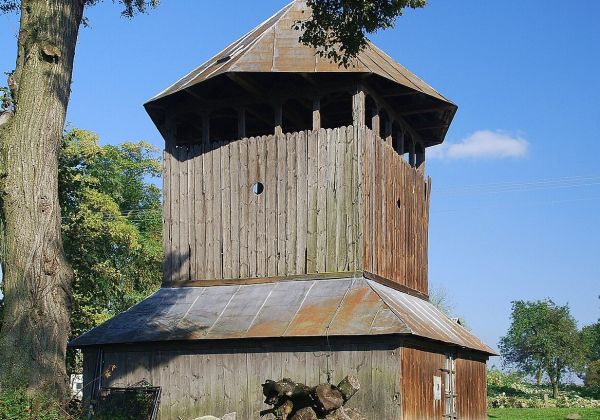 fot. Zabytkowa drewniana dzwonnica w Budyninie. Fot. Henryk Bielamowicz / Wikimedia Commons, CC BY-SA 4.0